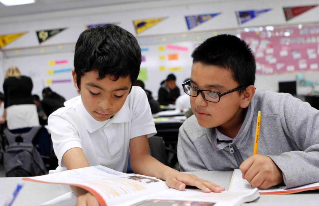 Two young students working together in a classroom.