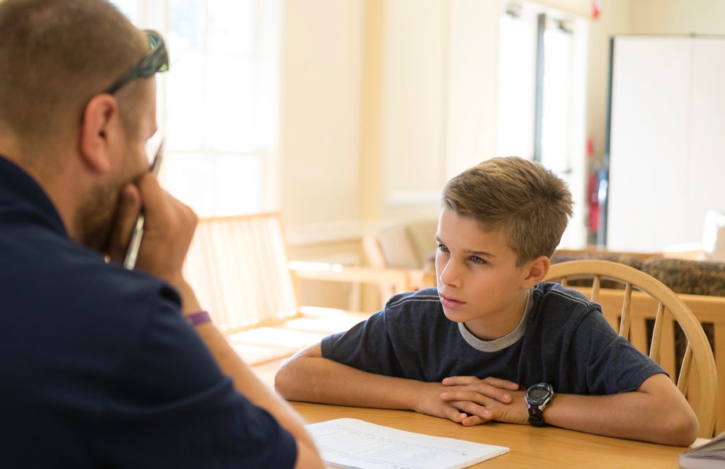 A student and a teacher having a discussion at a table.