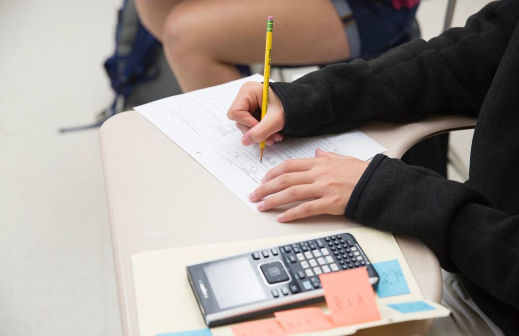 A student completing math problems with a calculator.