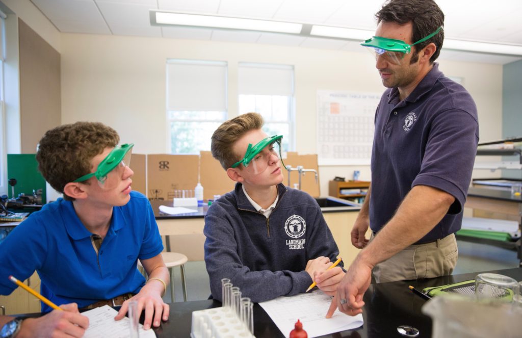 High school teacher and students are wearing safety googles during a science experiment.