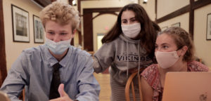 Three masked high school students collaborating on an activity.