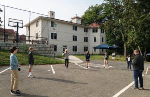Middle school students are socially distanced on the blacktop outside an academic building.