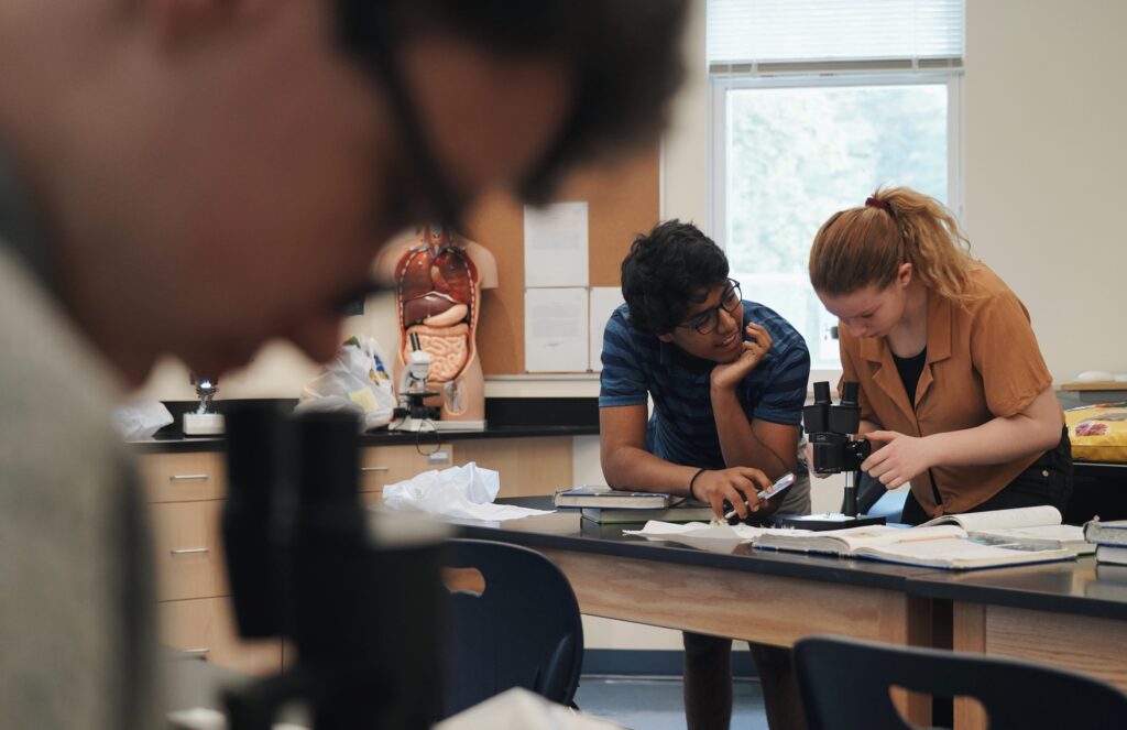 Two high school students sharing a microscope in a science lab.