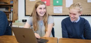 Two smiling Landmark High School students seated in front of a laptop.