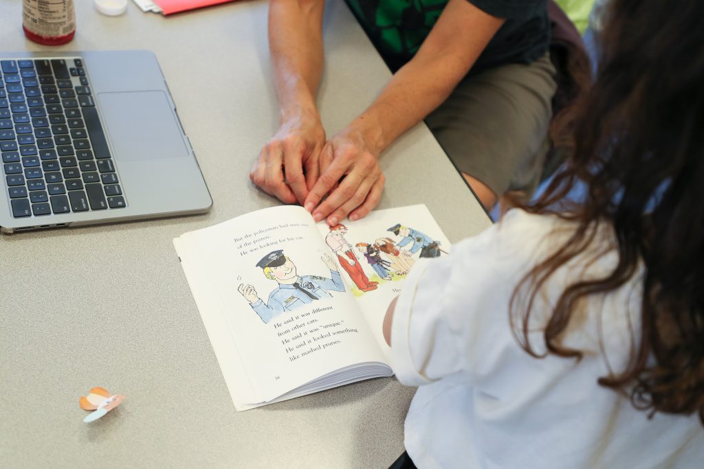 Teacher and elementary aged student reading picture book.