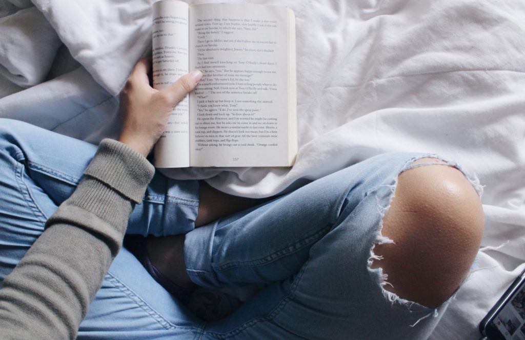 Cross legged student reading a novel.