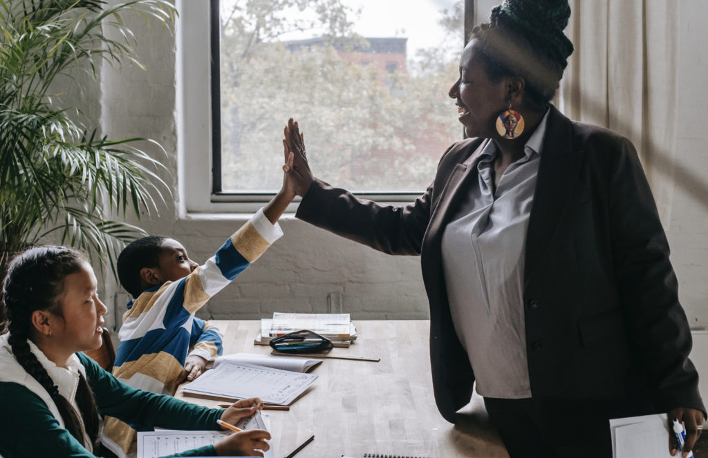 An educator is high-fiving her smiling student.